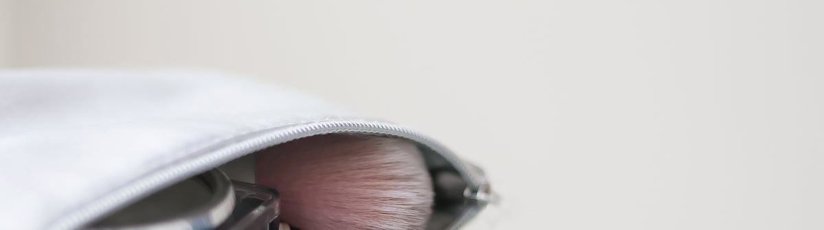 A make up bag laying sideway open with make up brushes and other items 